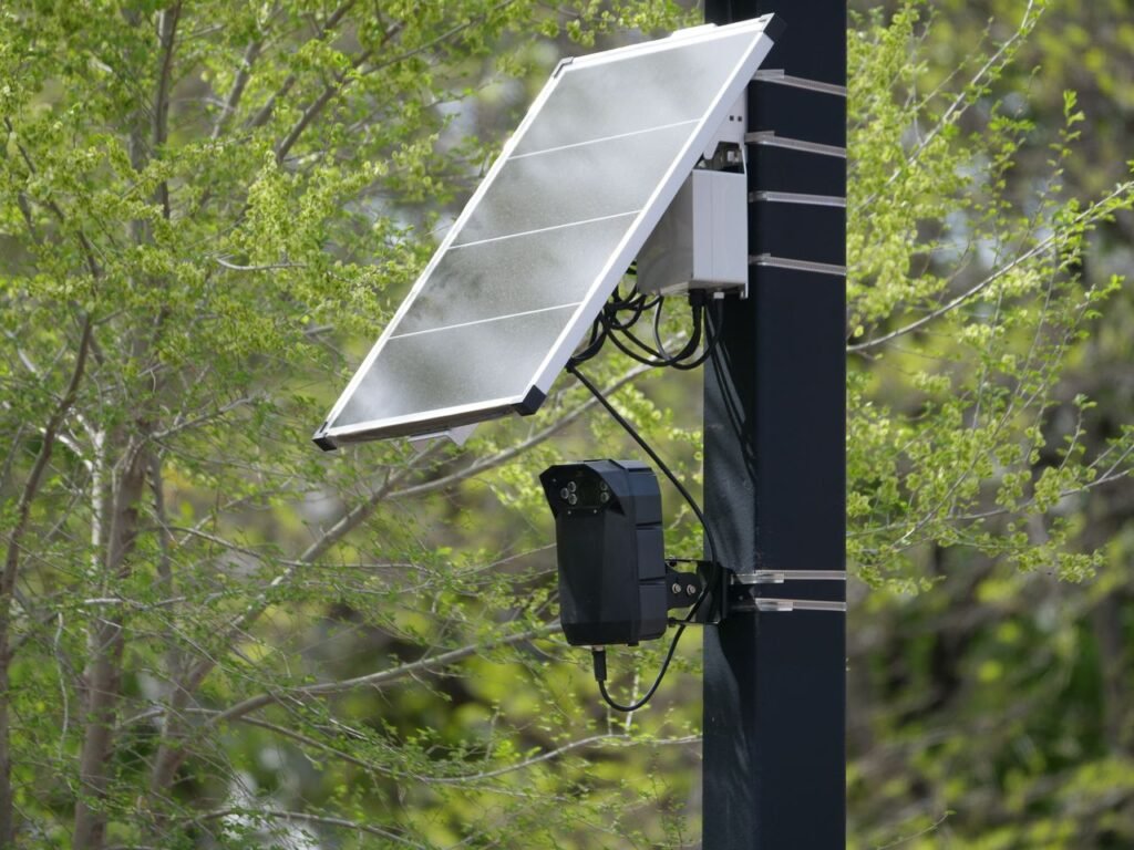 Solar-powered surveillance camera on a street pole surrounded by greenery, highlighting modern urban technology.