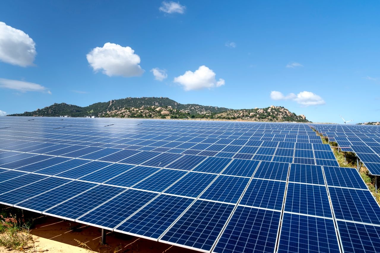 A sprawling solar farm with blue solar panels under a vibrant sky, showcasing renewable energy.